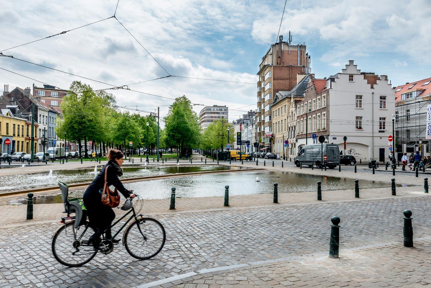 Biker moving on Quai du commerce, fountain and cars in the back