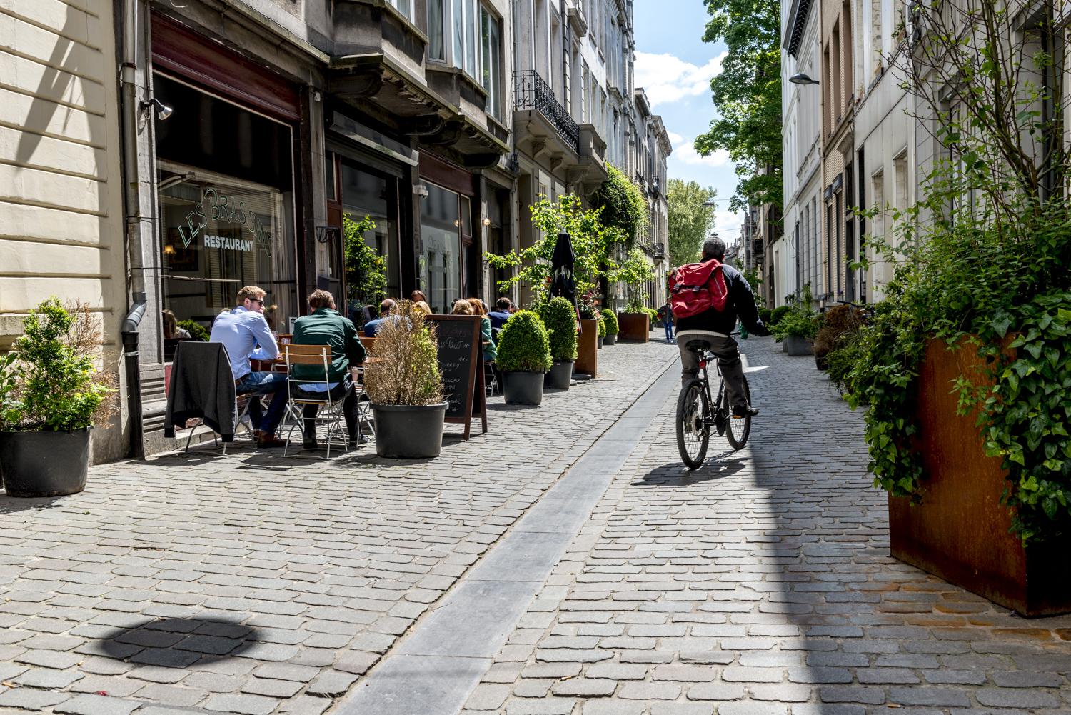 Biker moving on Rue Keyenveld, people sitting at restaurant